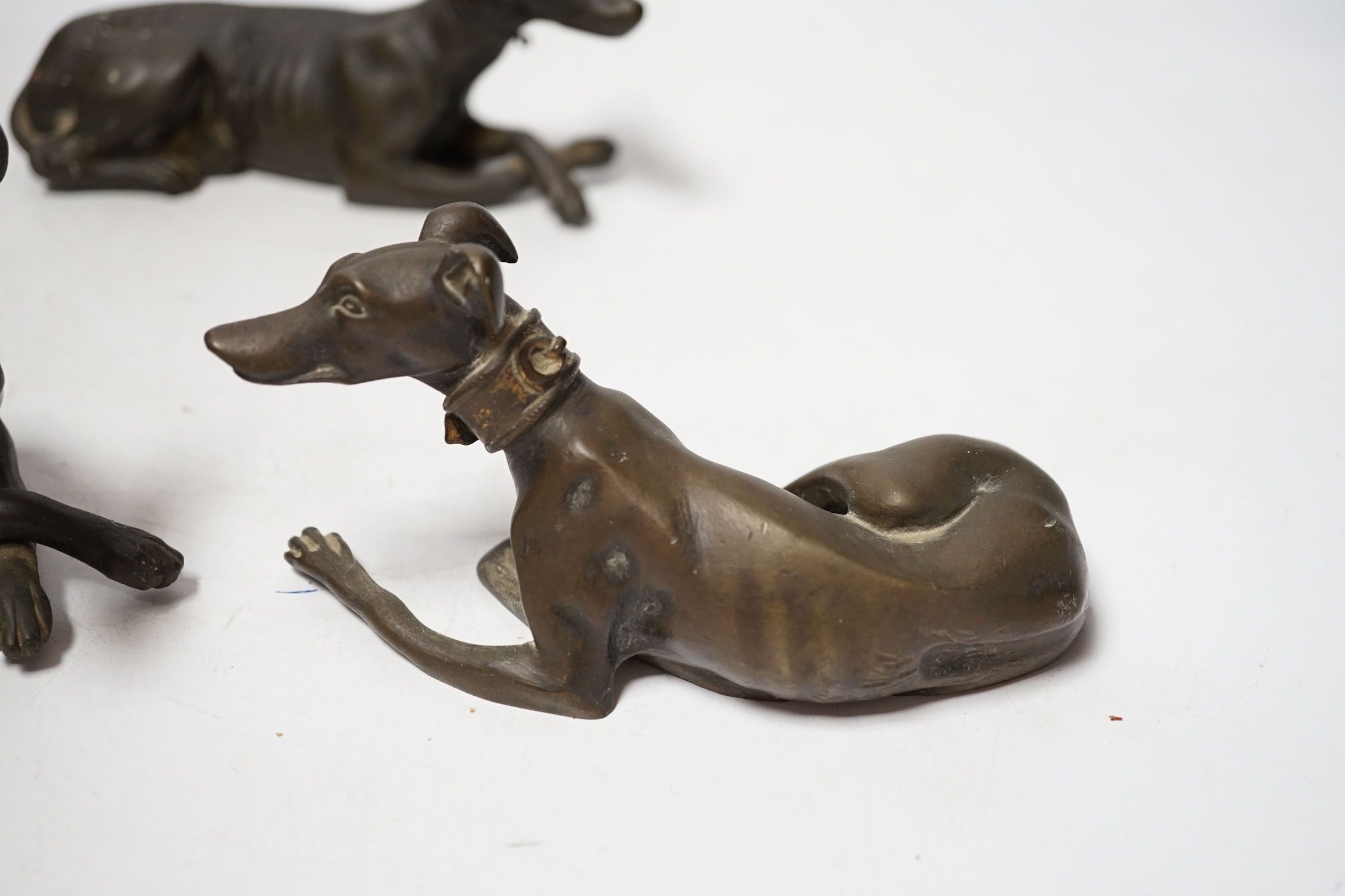 Three late 19th century bronze models of recumbent greyhounds, 17cm